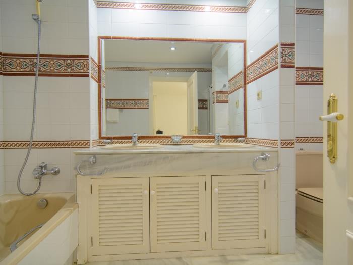 En suite bathroom with double sink, tub and shower