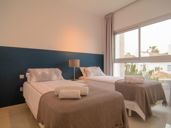 Two single beds and large windows in guest bedroom
