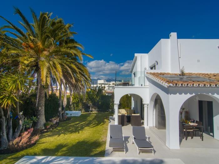 Manicured garden with exotic vegetation and sun loungers around the pool