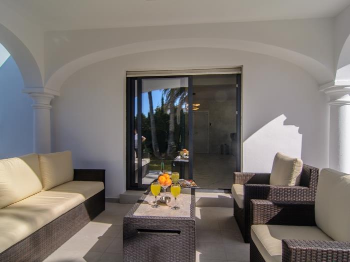 Comfortable rattan sofa and armchairs on sitting area with garden views