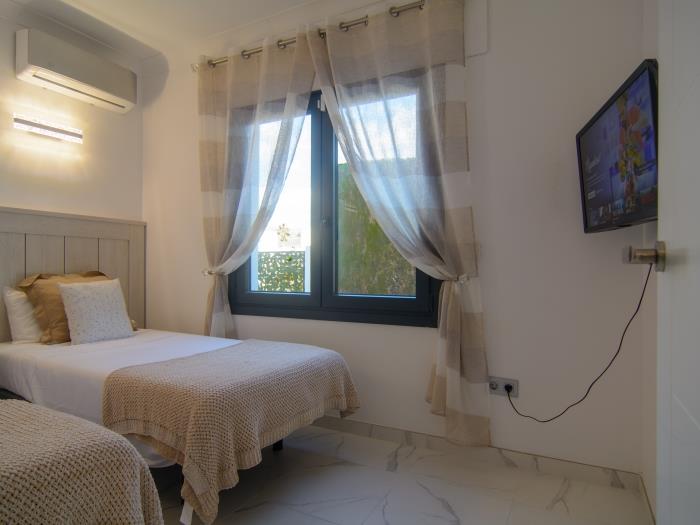 Guest bedroom with two single beds, wardrobe and TV