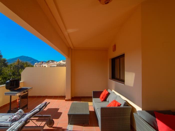 Lounge area on the terrace with sofas, coffee table, sun loungers and mountain views