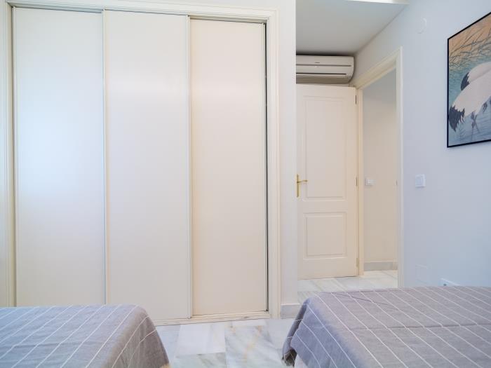 Bedroom with recessed wardrobes, air conditioner and marble floors