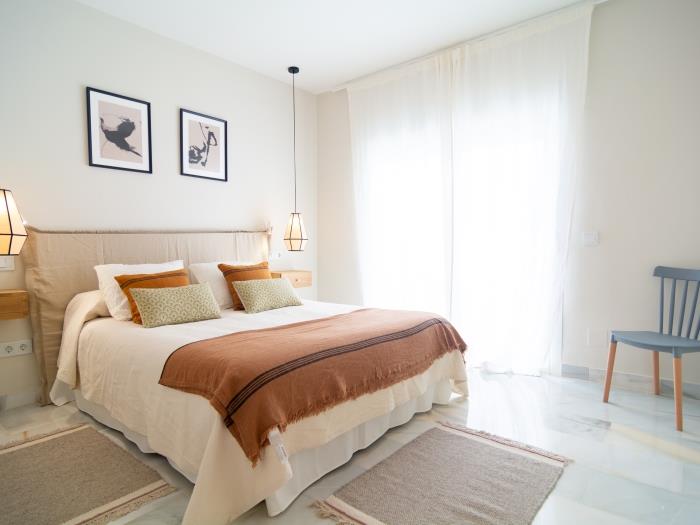 Bedroom with double bed and recessed wardrobes, chair, nightstands and lamps