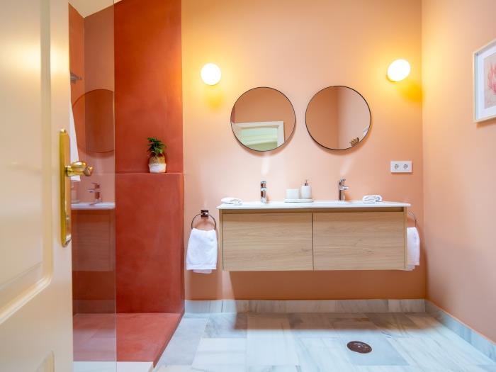 Family bathroom with double sink, two round mirrors, walk-in shower, rain-head shower