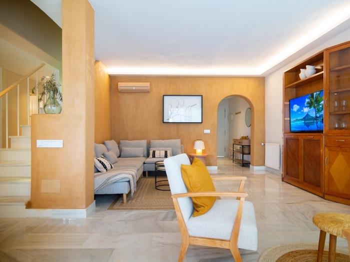 Living room with sitting area, TV, sofa and armchairs in a neat design